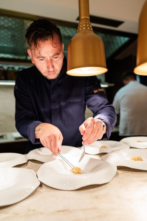 Kuchár pripravuje jedlo na tanieroch.