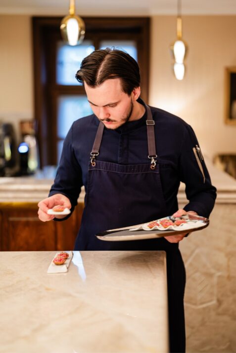 Kuchár pripravuje jedlo na tanieri.