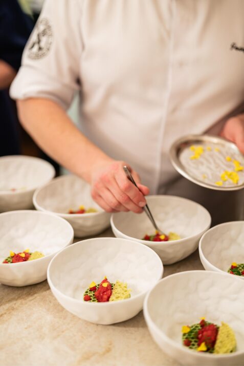 Kuchár pripravuje jedlo v miskách.