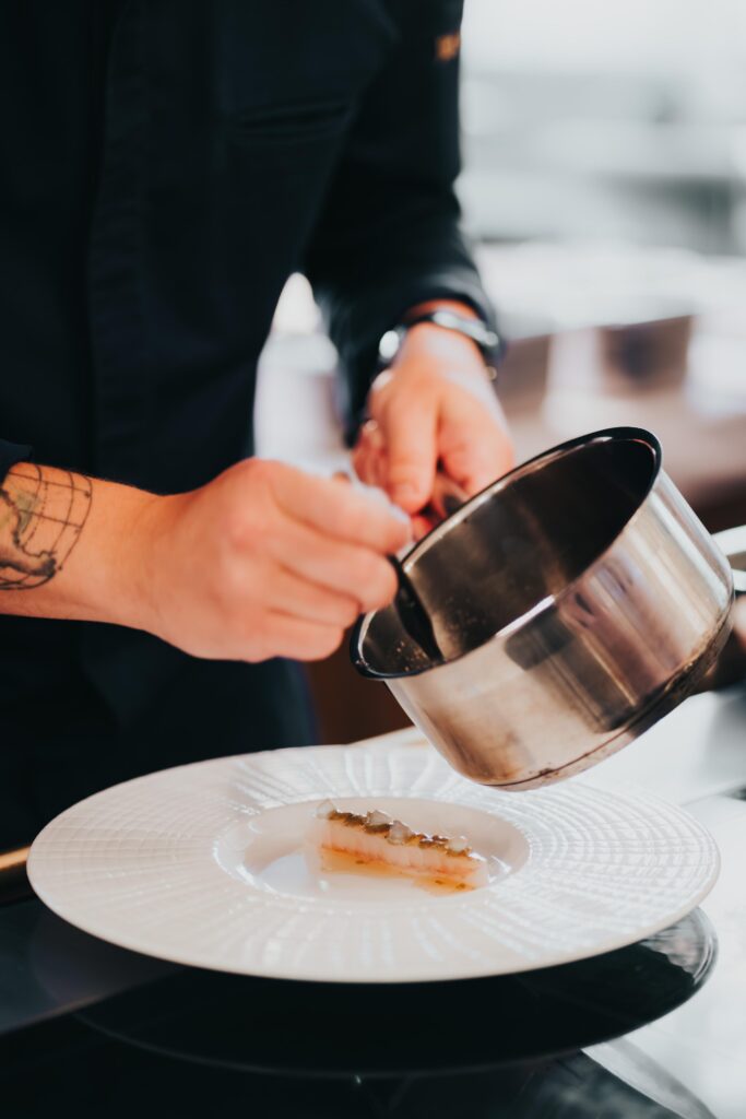 Kuchár servíruje jedlo na tanier.