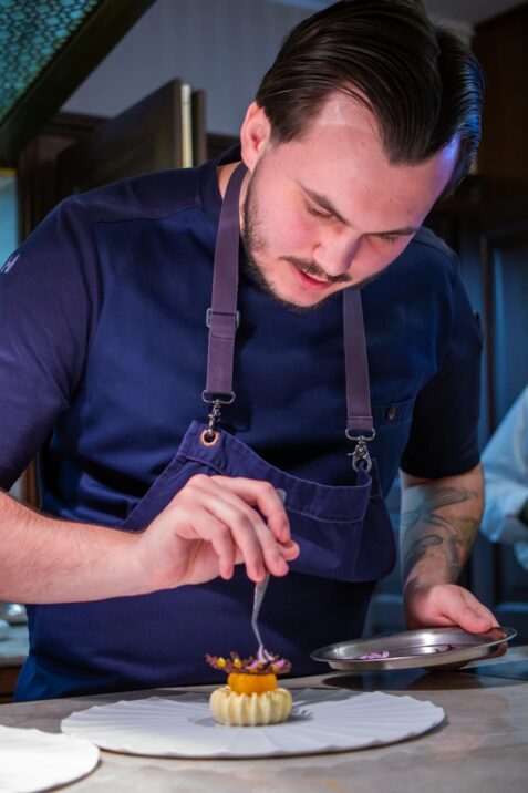 Kuchár pripravuje dezert na tanieri.